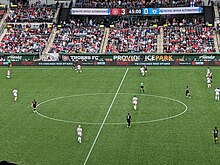 A view from the stands of Providence Park of Portland Thorns, in black football kit, and Chicago Red Stars, in white football kit, playing in front of an audience