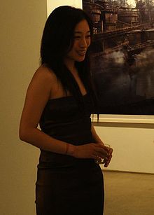 A long-haired East Asian woman in a black dress
