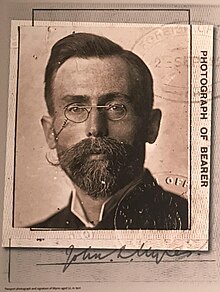 Headshot of a man with round glasses and a short, neat beard.