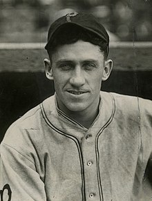 A man in a light baseball uniform and dark cap with a light "P" on the center