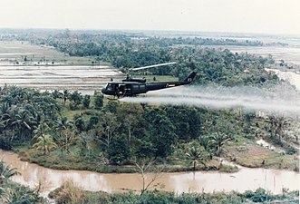 A US helicopter spraying Agent Orange on a jungle during the Vietnam War,
