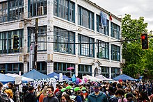 Crowded market in front of a large, white building
