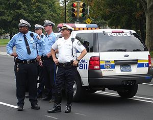 Philadelphia police officers standing next to a police SUV.