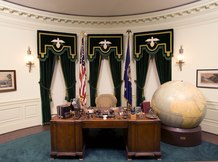 The Hoover desk with a large globe next to it in a recreation Oval Office.