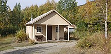 A cabin standing amongst tall trees in autumn.