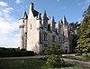 Vue d'un château montrant une échauguette à l'angle de deux murs au premier plan.