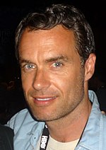 37-year-old man with short, dark hair smiling at the camera