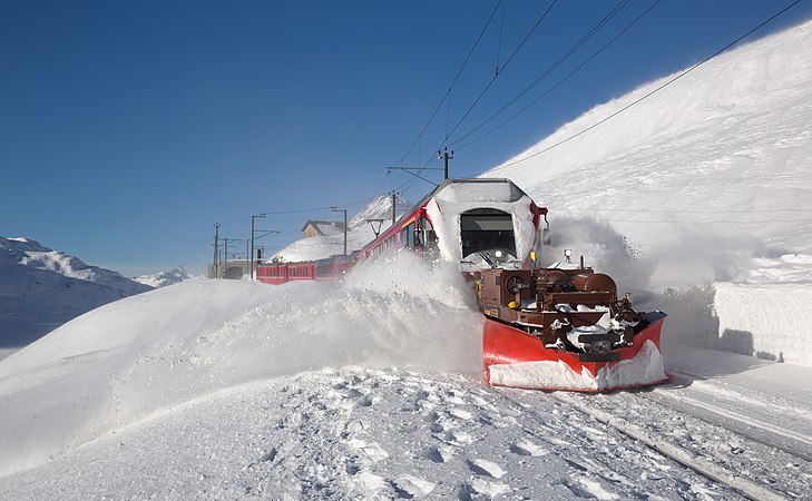 图为一辆开向意大利蒂拉诺的雷蒂亚铁路 ABe 8/12 形电车正在瑞士Ospizio Bernina车站（英语：Ospizio_Bernina_(Rhaetian_Railway_station)）附近铲雪。这辆列车的车头配备的是Xk 9144型雪铲。