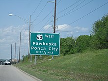 A large green road sign, reading "US-60 West/Pawhuska, Ponca City/Exit ½ Mile"
