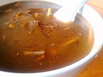 一碗胡辣汤，呈棕色粘稠状，内有羊肉等食品