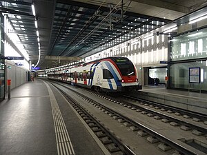 Red, white, and blue train on underground double-track railway line with side platforms