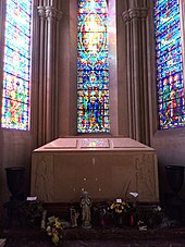 A large pink/cream-colored box in front of a stained glass window.