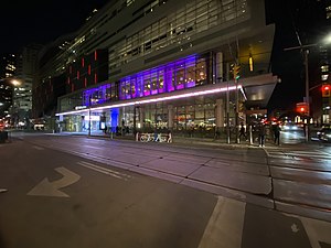 people milling around King Street in front of the TIFF Bell Lightbox, with rails and ropes set up around a carpets in front of the building