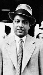 Black and white photograph of a man in suit and hat.