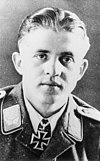 A man wearing a military uniform with an Iron Cross displayed at his neck.