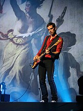 Berryman on stage with his bass, wearing a red shirt and black waistcoat