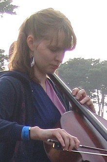 Hildur Guðnadóttir playing the cello. She is wearing a black dress, and looking down.