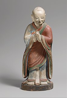 Monk in Chinese-style robes, bowing in respect with hands clasped and smiling