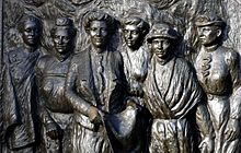 Close up of bronze bas-relief sculpture with six women grouped close together with warm and serious expressions, two of them wear hats and they are all wearing blouse and skirt type attire of the period. In addition Meri Te Tai Mangakāhia on the left has a cloak as well. Featuring leaders of the suffrage movement in New Zealand. From L to R: Meri Te Tai Mangakāhia, Amey Daldy, Kate Sheppard, Ada Wells, Harriet Morison, and Helen Nicol.