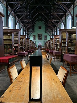 The Russell Library in Maynooth, looking from the west showing reading desks, shelves, the timber roof and paintings on the far wall.