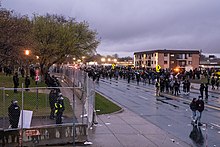 Protesters on the street outside the Brooklyn Center police department as law enforcement stand on the other side of a fence