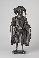 Figure E: Man wearing a chaperon (an elaborate hood popular in the mid-15th century). He has an elaborately ornamented belt, and his sleeves are unusually wide and flare at their ends. The cross around his neck reflects the Order of St. Anthony.[31]