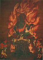 A deity with blue skin color seated on a pedestal and surrounded by flames. Two smaller figures are standing in the lower left and right corners.