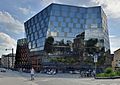 Freiburg's futuristic and modern University Library. The building is made of large angular glass and metal panels, and is a stark contrast to the older buildings distantly present in the picture.