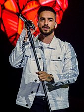 A Latin man is performing whle holding the microphone