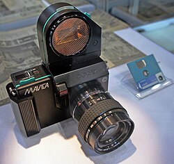 Prototype Sony Mavica still video camera from 1981. This prototype camera is a black-colored rectangular box with a projecting cylindrical lens.