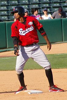 A man wearing a red baseball jersey with "Sounds" written across the chest, gray pants, and a black batting helmet stands on second base.