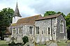 A flint church with a red tied roof and a tower at the west end, seen from the southeast