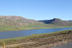 A body of water running alongside a long hill