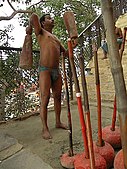 J-24. (Remaining Traditional) Using traditional long dumbbells, a pehlwan wrestler stays fit in an Akhara