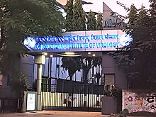 Entrance gate with name of institution illuminated on a banner on top