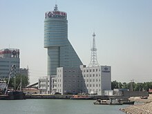 A wharf with several ships berthed, and a high rise building on the background