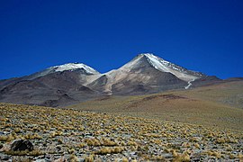 乌图伦古火山 (Uturuncu) 是一片荒凉景观中的一座圆锥体，旁边有一座较小的非圆锥状山峰。