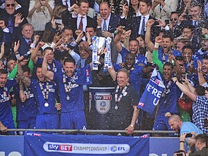 A football team celebrating and lifting a trophy.