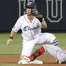 Maggi kneeling on a base as a baserunner slides into it