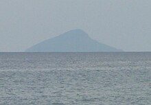 The island photographed from a great distance, which results in the image only revealing the island's outline.