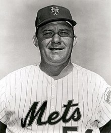 A man in a white baseball uniform with "Mets" on the chest and a dark cap.