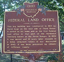 historical marker saying Federal Land Office This log building was constructed in 1801 by David Hoge on the west side of Third Street. It served as his home and as the first Federal land office in that part of the Northwest Territory known as the Seven Ranges. In 1809 it was moved, and twelve years later encased in a brick structure where it was discovered in 1940. It has been preserved by the citizens of Jefferson County.