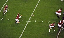 A holder receives the snap with the kicker preparing to kick the ball.