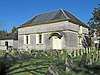 A small, rectangular building next to some gravestones.