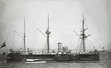 A three-masted black and white ship at port.
