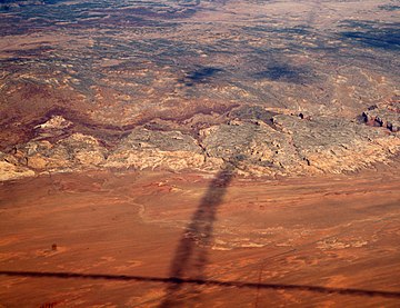 Shadows of contrails over San Rafael Reef — San Rafael Swell, Reef (perimeter), and San Rafael Desert at south & southeast. The Reef is most of the southeast, and east perimeter of the 45-mile-wide (72 km) (west-to-east) San Rafael Swell, which trends southwest-by-northeast.
