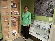 Dorothy Gunderson, of the Sunnyslope Historical Society and Museum, poses in front of the John C. Lincoln display in the historical building which once housed the Peoples Drug Store.