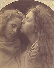 A woman's cheek rests on the forehead of a younger girl. Both appear calm and are draped in fabric from the neck down.