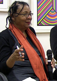 A portrait of bell hooks, black woman with glasses speaking