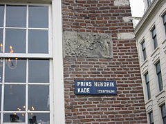 Above the street name sign 'Prins Hendrikkade' is a tablet with the old name: 'Scrayer-Houck'.